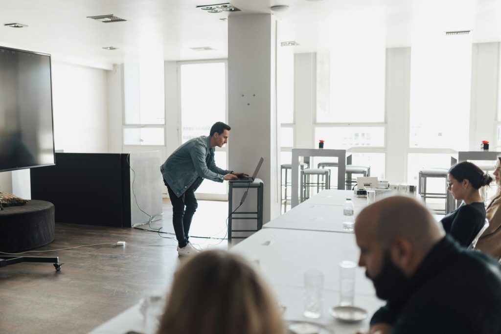 A professional presenting in a bright modern office setting to attentive colleagues.