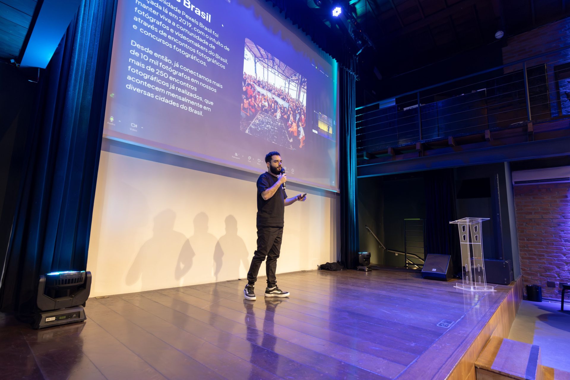 Speaker presenting at a conference with a projected presentation slide on screen.
