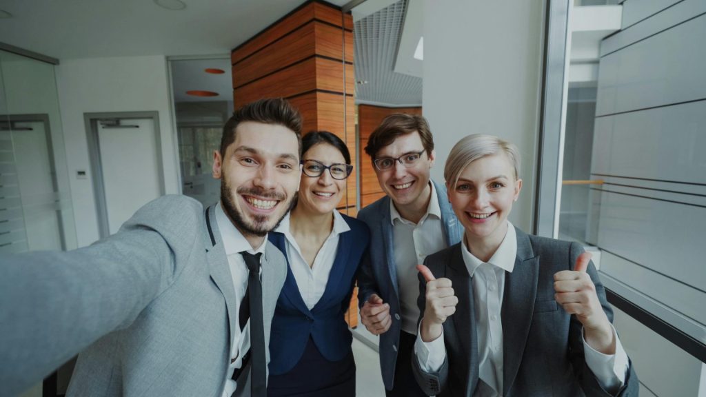 A cheerful business team taking a selfie in a modern office setting.
